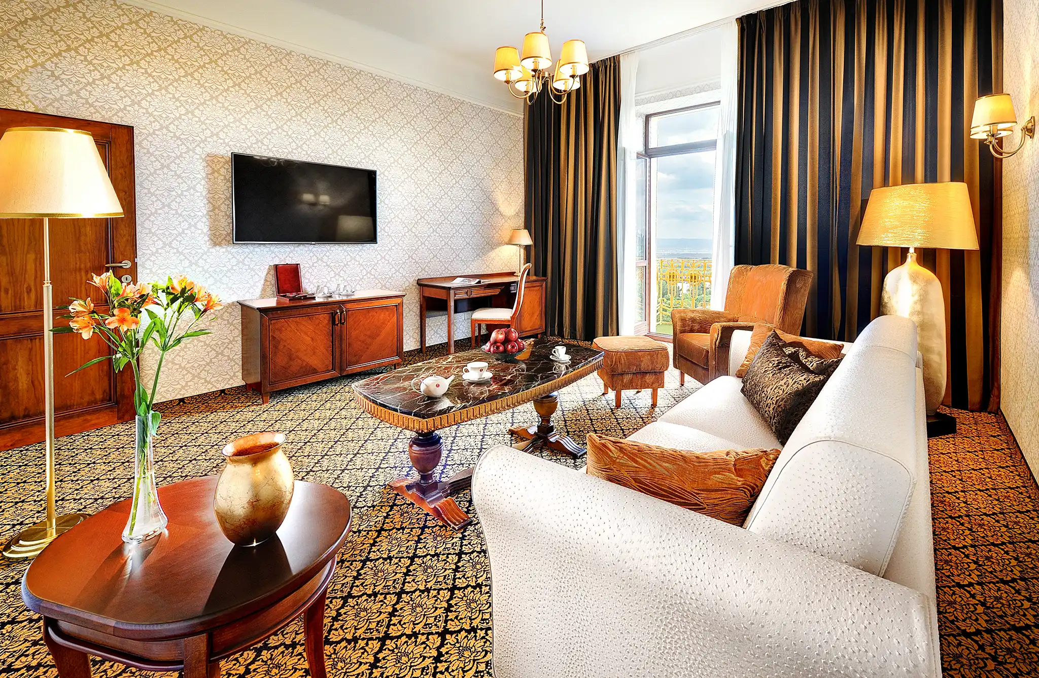 Apartmán Classic Grandhotela Praha so vzorovanými tapetami a kobercom, tmavými závesmi a svetlým posedením
