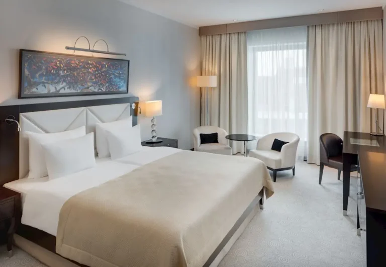 Vendégszoba a pozsonyi Grand Hotel River Park***** szállodában világos sötétítő- és fényáteresztő függönyökkel, mintás padlószőnyeggel